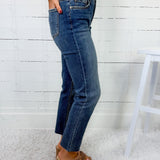 Person wearing blue jeans and a white sweater against a white wooden panel background