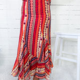 Person wearing a colorful patterned dress with a white wooden floor background