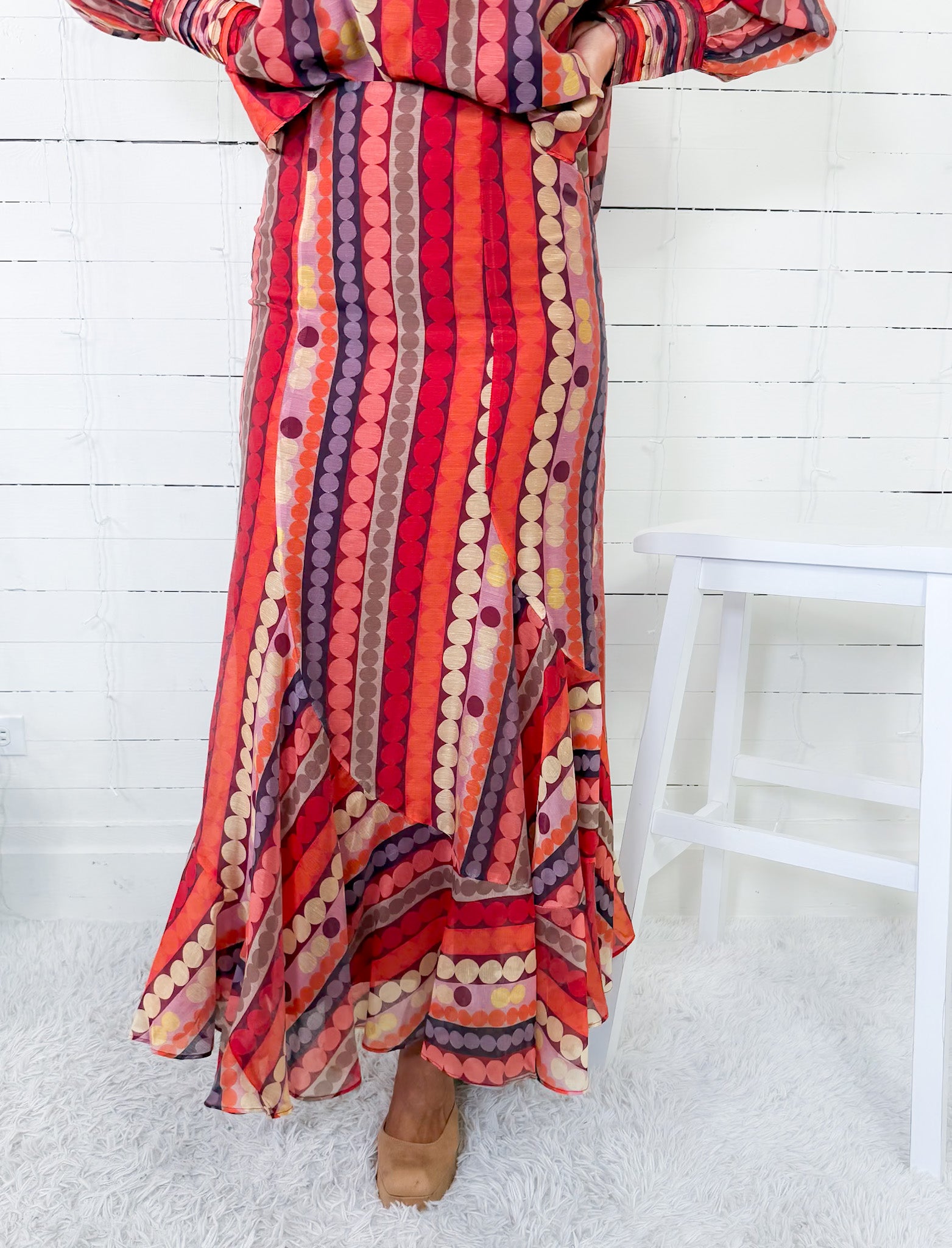 Person wearing a colorful patterned dress with a white wooden floor background