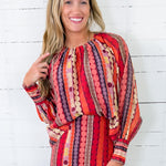 Woman wearing a colorful patterned dress against a white wooden background