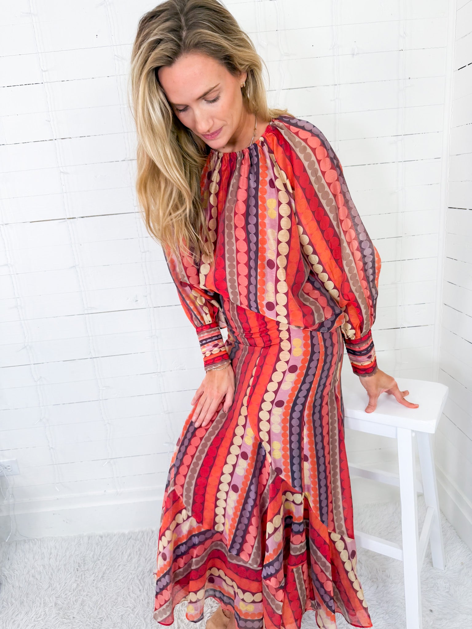 Woman wearing a colorful patterned dress against a white background