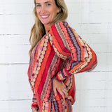 Woman wearing a colorful patterned dress against a white wooden background