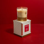 Votivo candle on its packaging against a red background