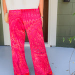 Person wearing bright pink patterned pants standing on a porch.