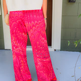 Person wearing bright pink patterned pants standing on a porch.