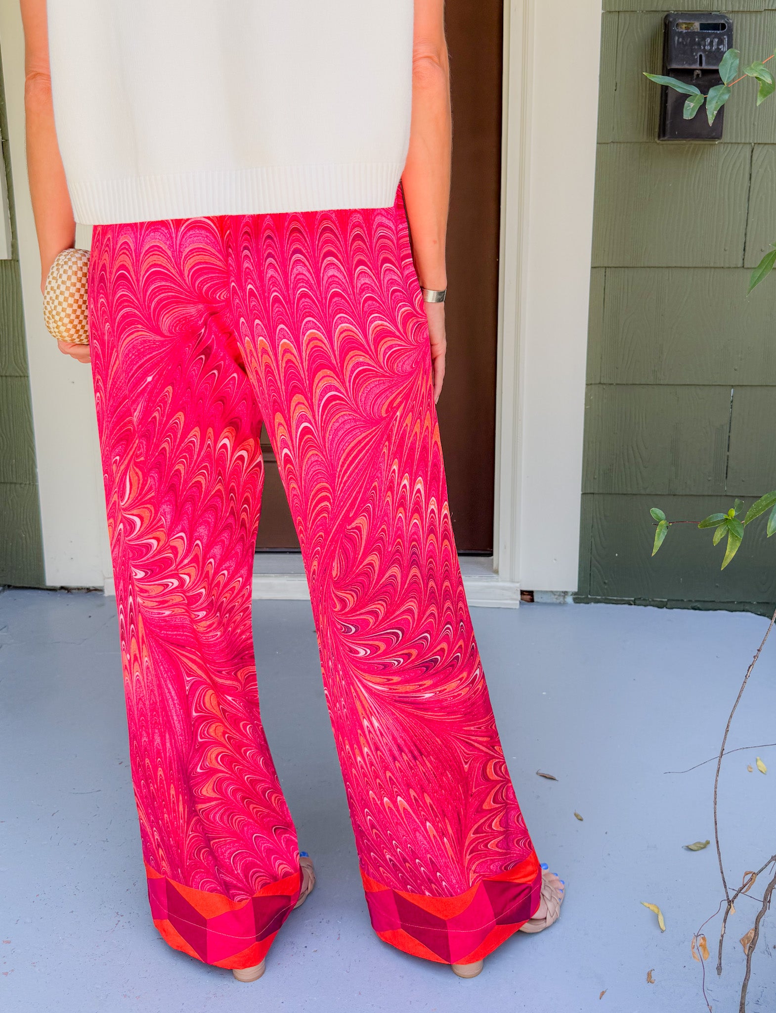 Person wearing bright pink patterned pants standing on a porch.