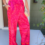 Person wearing bright pink patterned pants standing on a porch.