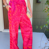 Person wearing bright pink patterned pants standing on a porch.