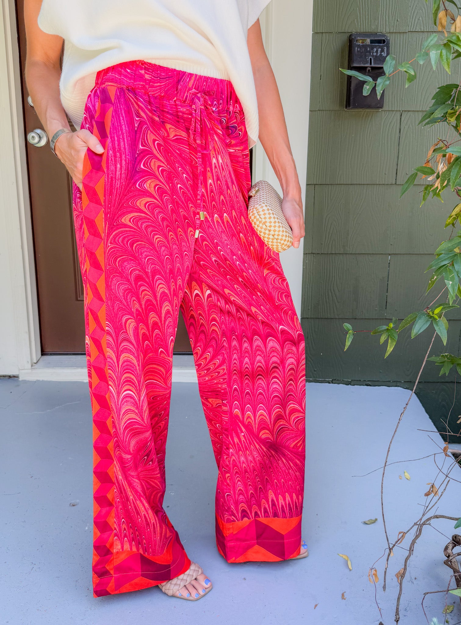 Person wearing bright pink patterned pants standing on a porch.