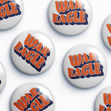 Several round white button badges with the words "WAR EAGLE" in orange and navy blue are arranged on a light gray background.