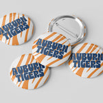 Four round pin-back buttons with the Auburn Tigers logo, showing both front and back views on a light gray background.