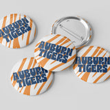 Four round pin-back buttons with the Auburn Tigers logo, showing both front and back views on a light gray background.
