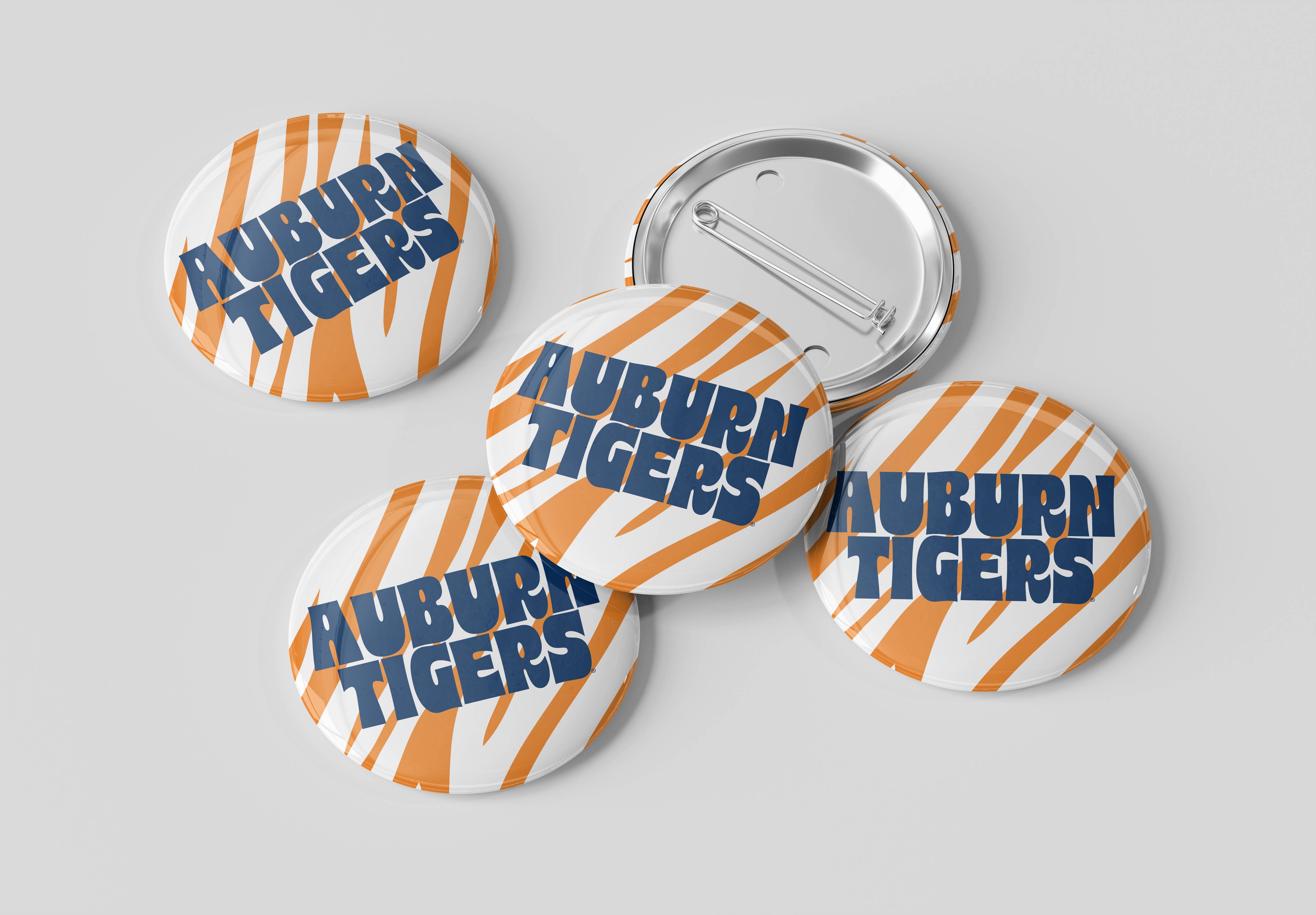 Four round pin-back buttons with the Auburn Tigers logo, showing both front and back views on a light gray background.