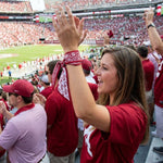 Woman in a red sports jersey cheering at a stadium with fans in the background