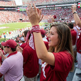 Woman in a red sports jersey cheering at a stadium with fans in the background