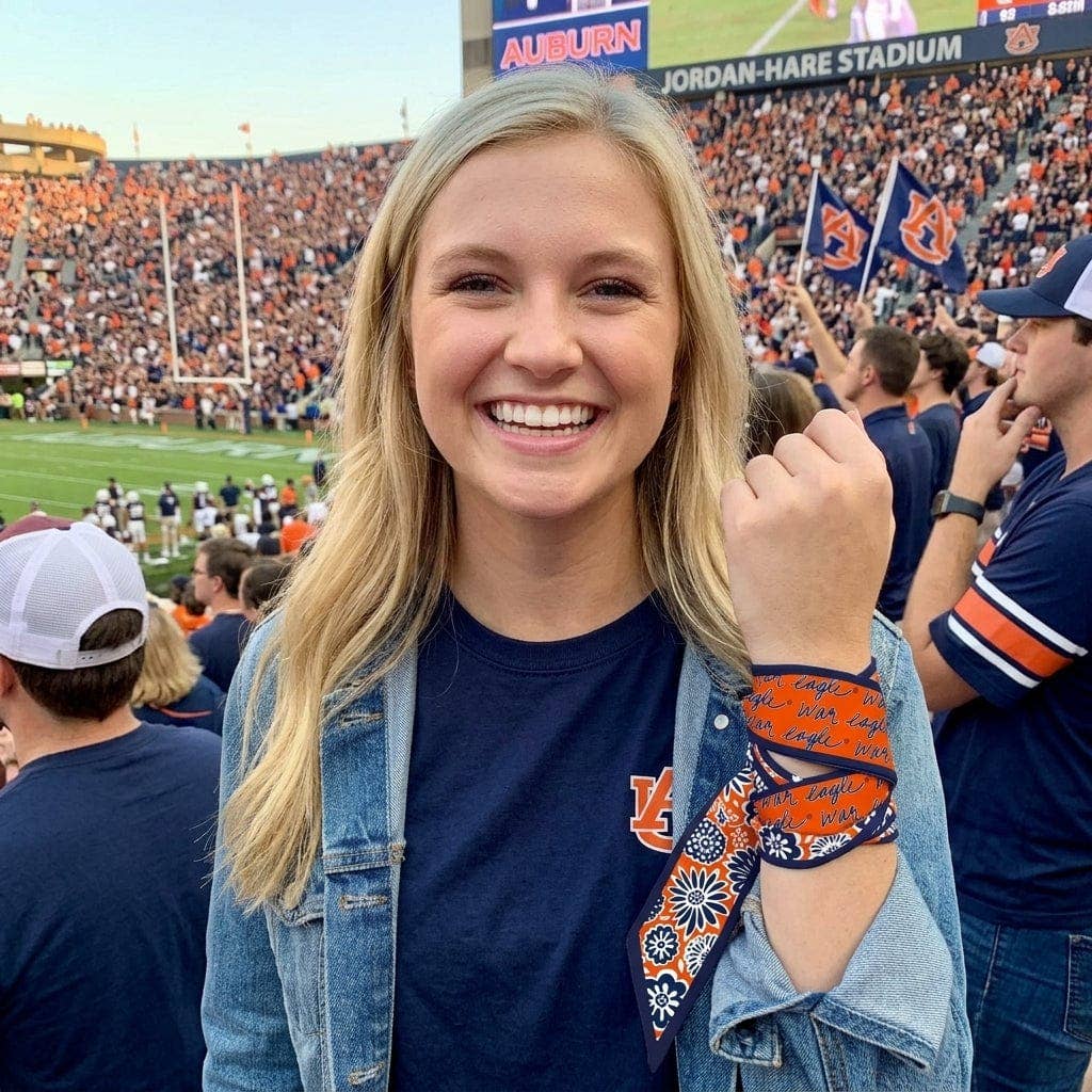 Woman at Auburn football game with stadium and fans in the background