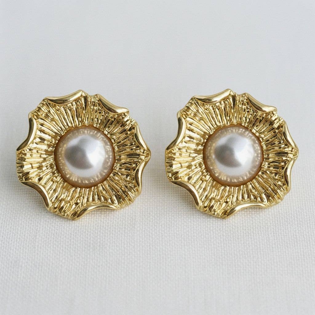 Pair of gold earrings with pearl centers on a light gray background