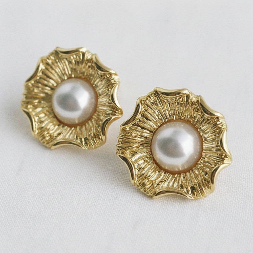 Pair of gold earrings with pearl centers on a light gray background