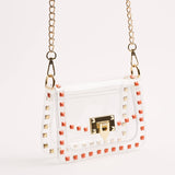 White handbag with gold accents and red studs on a white background