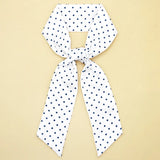 White scarf with navy blue polka dots on a beige background