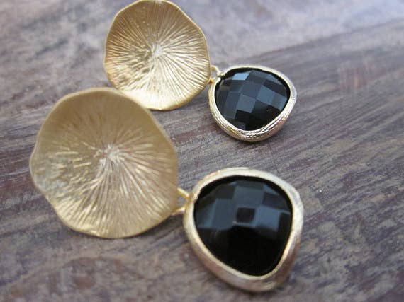 Pair of gold earrings with black stones on a wooden surface