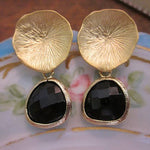 Gold earrings with black stones on a decorative plate