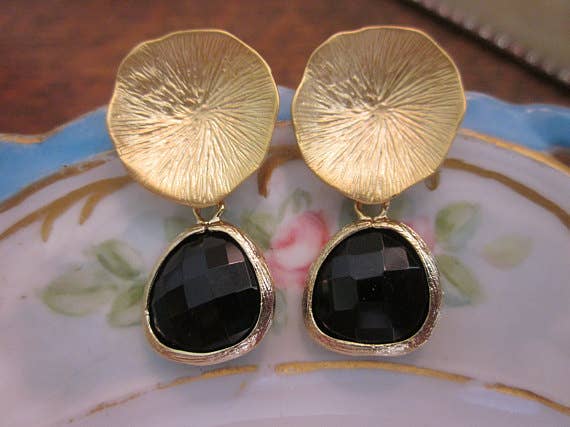 Gold earrings with black stones on a decorative plate