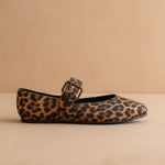 Leopard print flat shoe with a buckle on a beige background