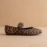 Leopard print flat shoe with a buckle on a beige background