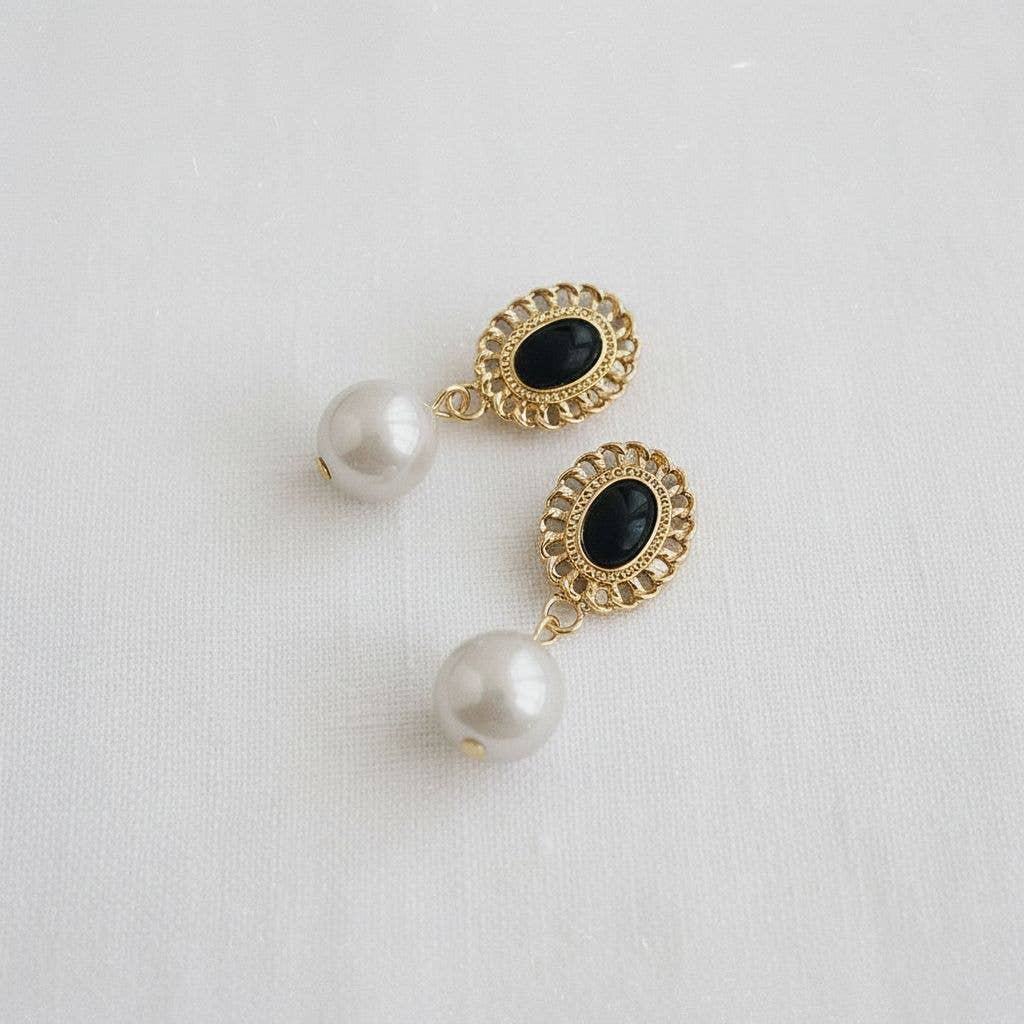 Pair of earrings with gold and black details on a light gray background