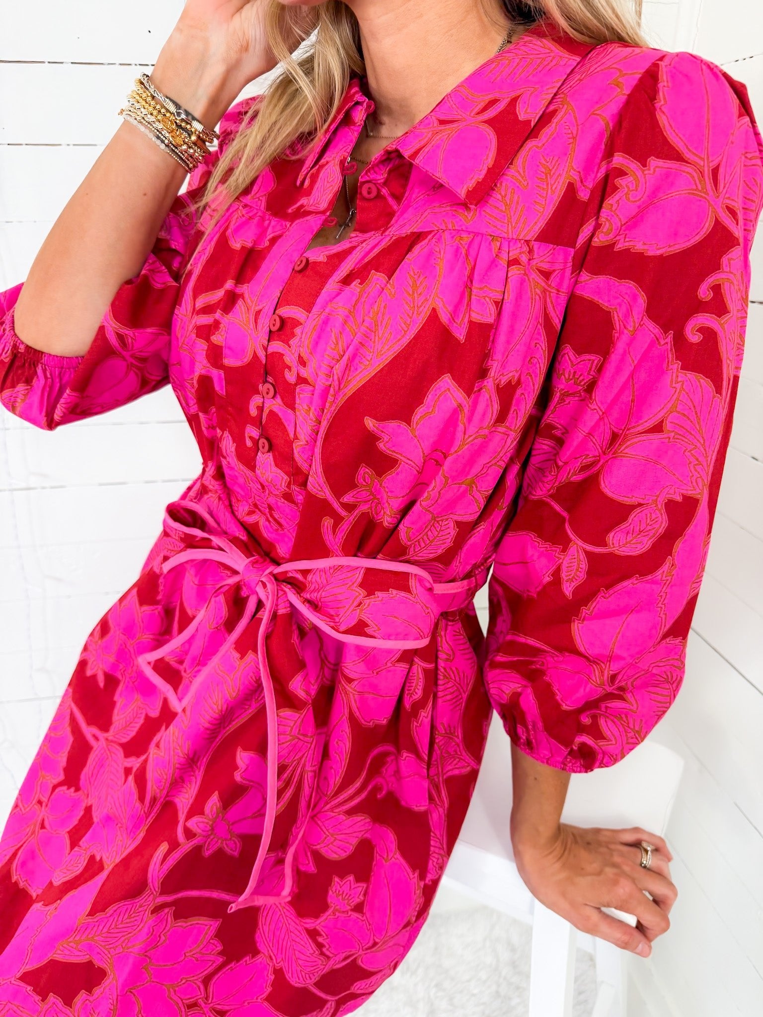 Person wearing a bright pink floral dress on a white background