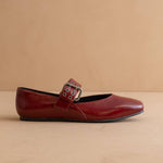 Red flat shoe with a buckle on a beige background