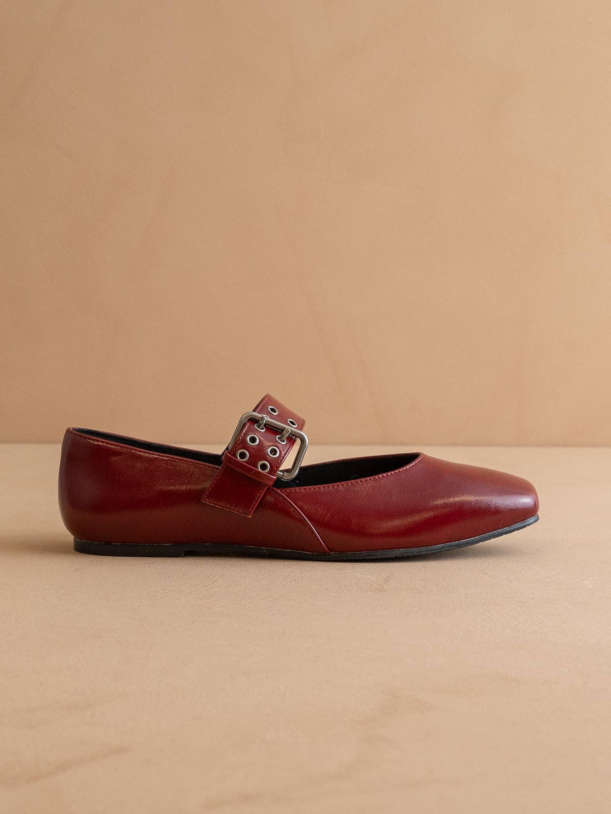 Red flat shoe with a buckle on a beige background