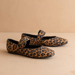 Pair of leopard print shoes with buckles on a beige background