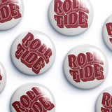 Several round white button badges with the words "ROLL TIDE" in large red stylized lettering, arranged on a light gray background.
