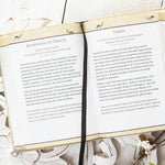 Open book with text on a decorative surface with plants and flowers
