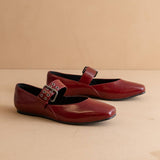 Pair of red shoes with buckles on a beige background