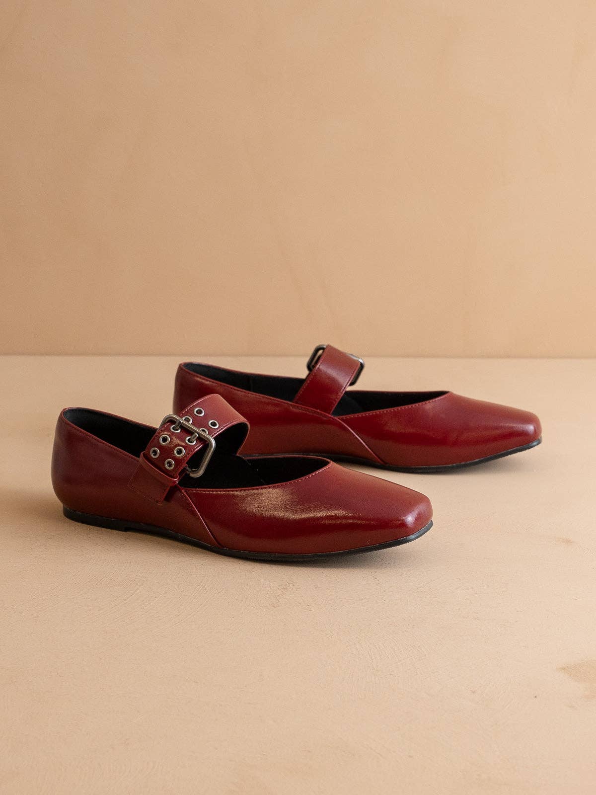Pair of red shoes with buckles on a beige background