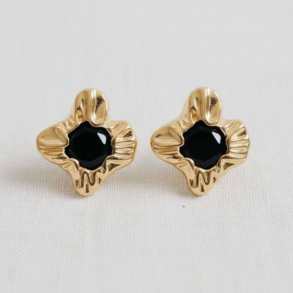 Gold earrings with black centers on a light gray background