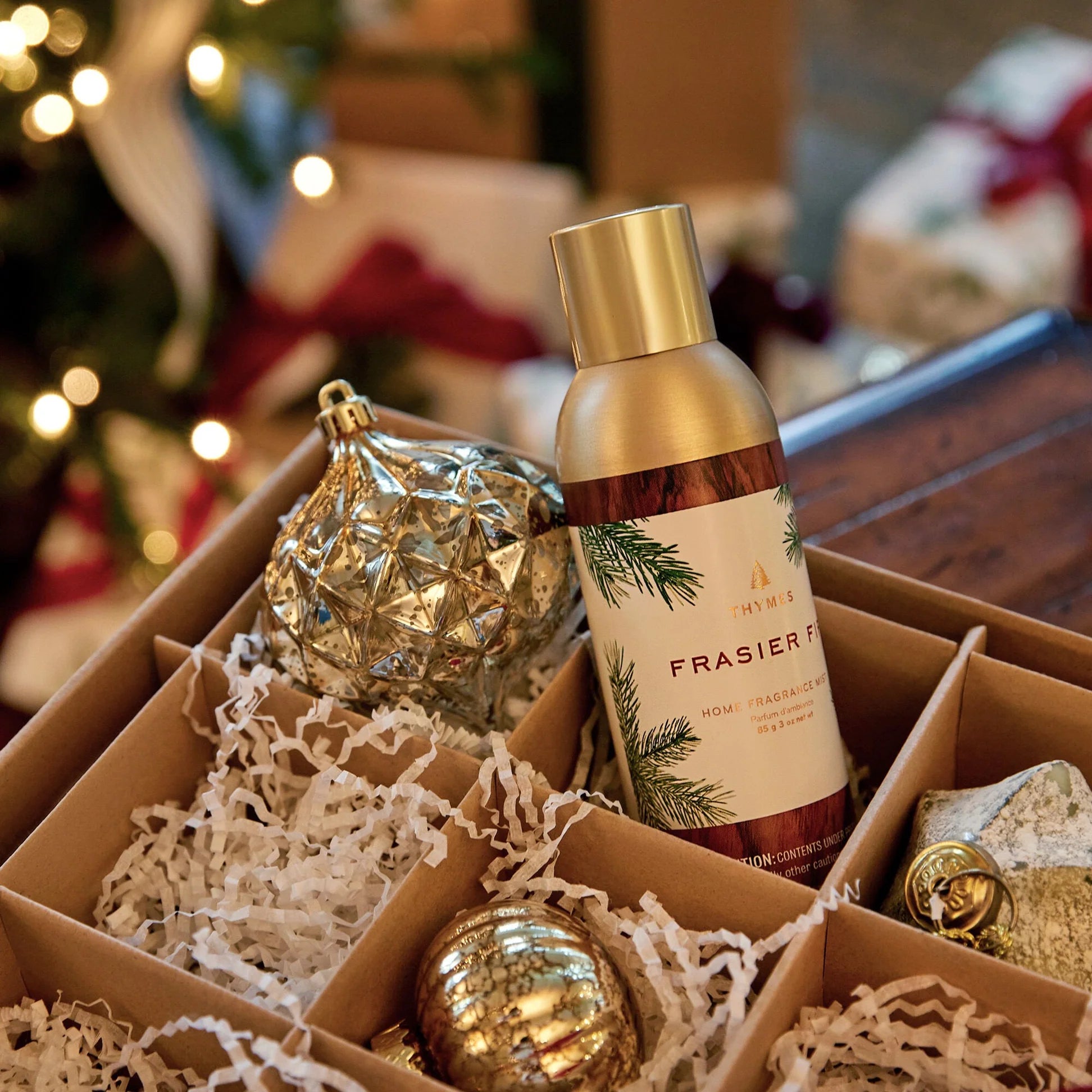 Frasier bottle in a decorative box with Christmas ornaments and lights in the background