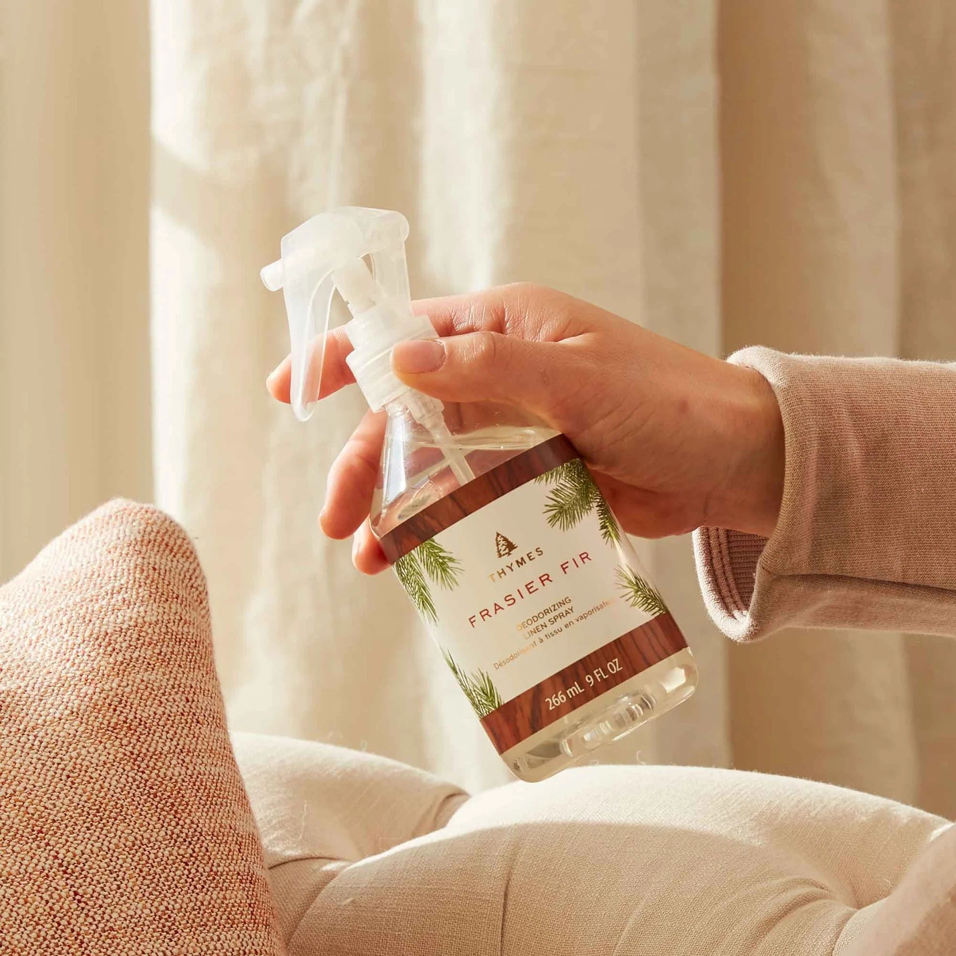 Hand holding a 'Frasier Fir' room spray bottle with a neutral background
