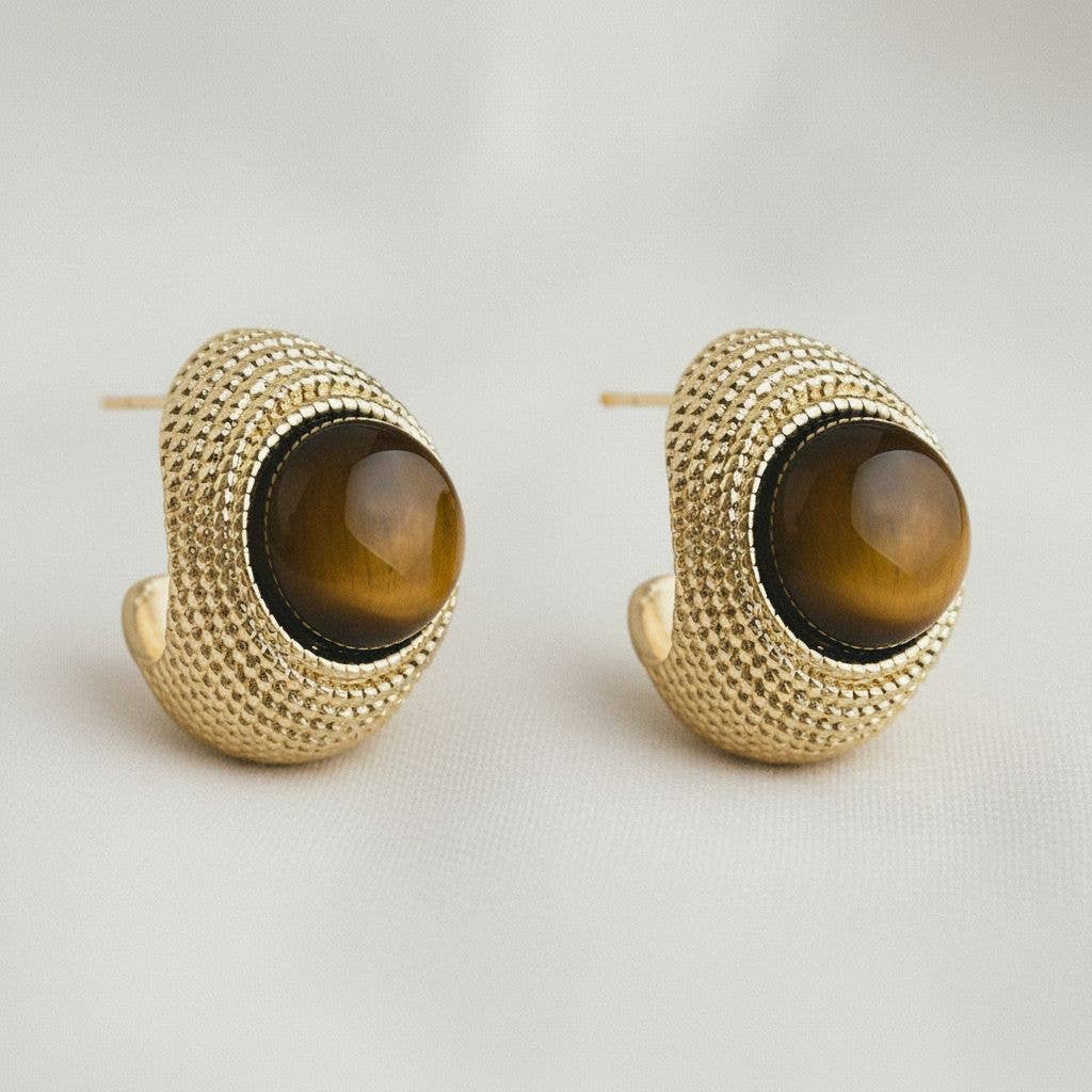 Pair of gold hoop earrings with brown gemstones on a light gray background
