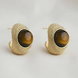 Pair of gold hoop earrings with brown gemstones on a light gray background