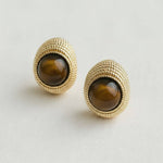 Gold earrings with brown gemstones on a light gray background