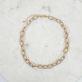 Gold and silver chain necklace on a marble surface