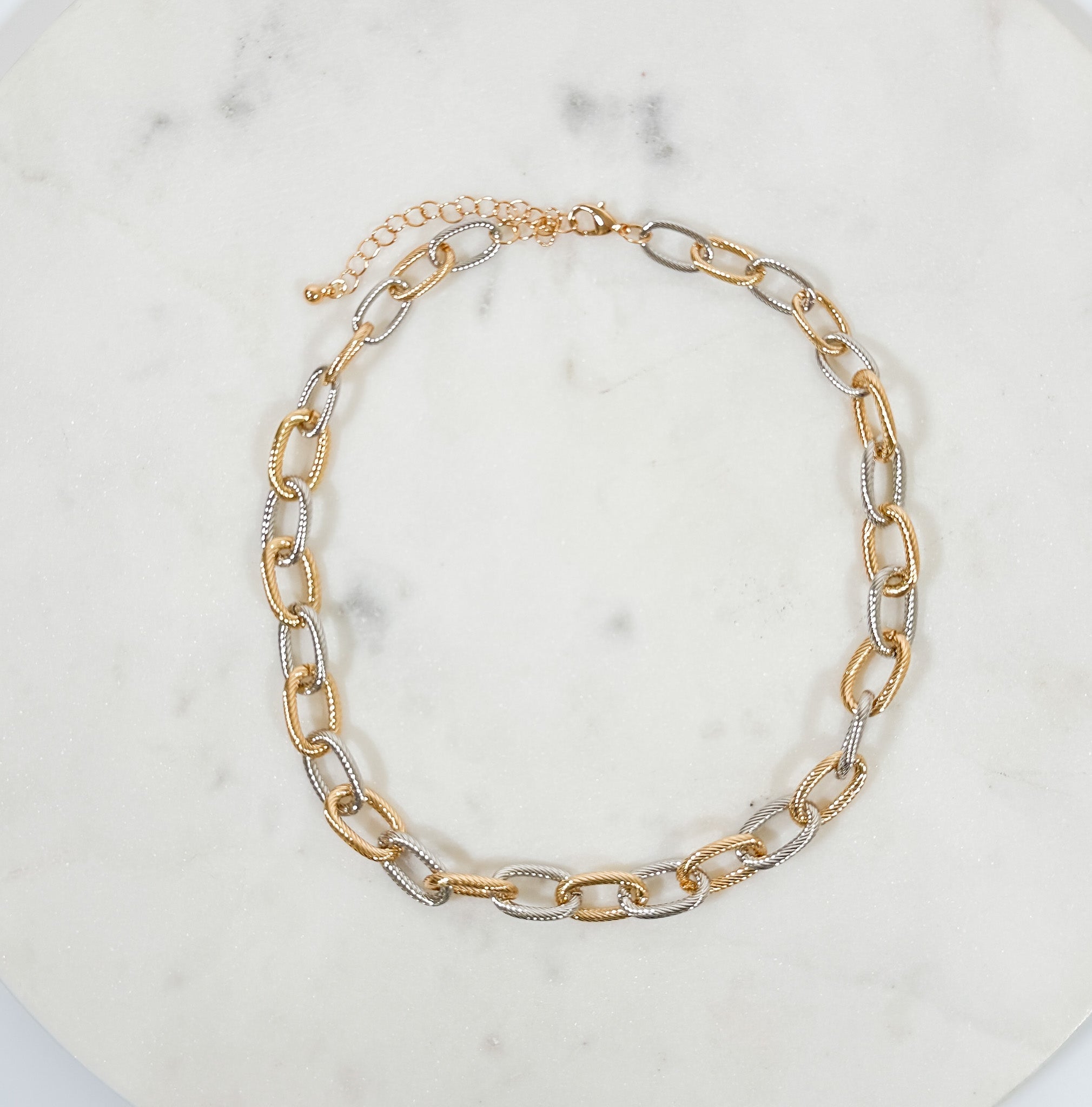 Gold and silver chain necklace on a marble surface