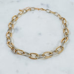 Gold and silver chain bracelet on a marble surface