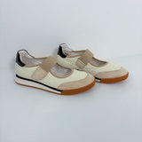A pair of women's casual Mary Jane-style shoes in cream and beige, featuring a hook-and-loop strap, black heel accents, and brown soles, photographed on a light gray studio background.