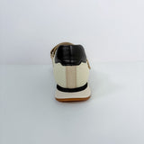 A single low-top shoe shown from the back, featuring an off-white leather upper with a black leather heel tab, a black horizontal stripe, and a tan sole.