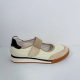 A single women's casual shoe shown in profile against a plain light gray background. The shoe features an off-white leather upper with beige suede panels, a beige hook-and-loop strap, a black heel tab, and a brown gum outsole.